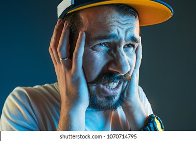 Sports, Fan Human Emotions And People Concept - Sad Young Man Watching Sports On Tv And Supporting Team At Home. Crying Emotional Man Screaming In Colorful Bright Lights At Studio. Facial Expression