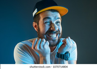Sports, Fan Human Emotions And People Concept - Sad Young Man Watching Sports On Tv And Supporting Team At Home. Crying Emotional Man Screaming In Colorful Bright Lights At Studio. Facial Expression
