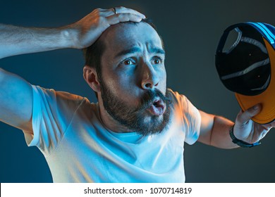 Sports, Fan Human Emotions And People Concept - Sad Young Man Watching Sports On Tv And Supporting Team At Home. Crying Emotional Man Screaming In Colorful Bright Lights At Studio. Facial Expression