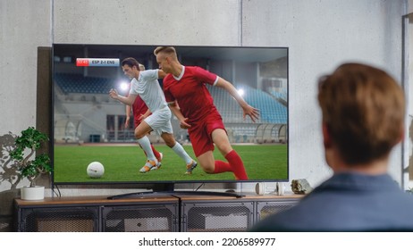 Sports Fan Watches Important Soccer Match on TV at Home, He Is Focused on Intense Championship, Cheering for His Team. His Favourite Football Team Scores and Leading the Game. - Powered by Shutterstock