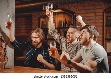 Sports Fans Funny Friends Men Sit In Bar Drink Beer And Watch Football Match On TV In Pub.