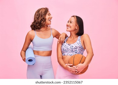 Sports, fitness and women on pink background for yoga, training and exercise with ball and yogi mat. Friends, happy and people in studio with gym equipment for wellness, workout and healthy body - Powered by Shutterstock