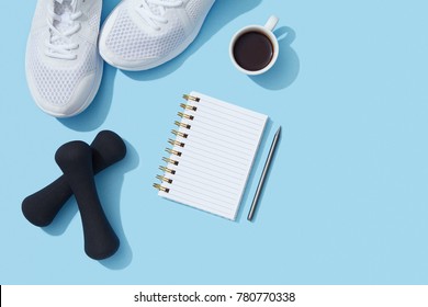 Sports Flat Lay With Coffee, Dumbbells, Sneakers And Notebook On Blue Background