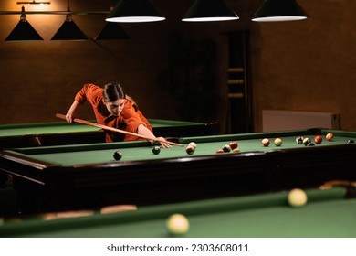 Sports game of billiards on a green cloth. Woman playing with Multi-colored billiard balls and cue on a pool table. Billiard sports concept.