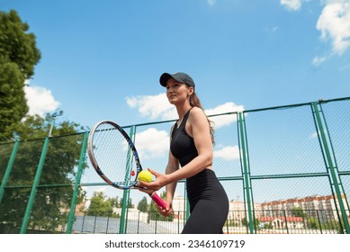 Sports girl with racket and tennis ball. A beautiful young girl is exercising. The tennis player is preparing to serve. - Powered by Shutterstock