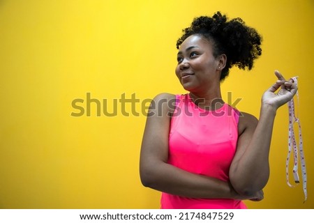 Sports girl in studio. Fat burning after intense exercise. A woman measures the size of the muscles with a measuring tape. The growth of muscle mass for strong body. Positive thinking for all story
