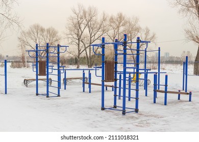 Sports Ground For Street Workout In Winter Park. Free Outdoor Gym. Outdoors Gym And Fitness Equipment At The Public Park. Empty Snowy Workout Ground. Area With Exercise Equipment