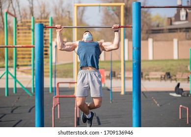 A Sports Guy Pulls Himself Up On A Horizontal Bar In A Medical Mask During A Pandemic. COVID-19. Health Care.