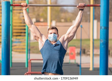 A Sports Guy Pulls Himself Up On A Horizontal Bar In A Medical Mask During A Pandemic. COVID-19. Health Care.