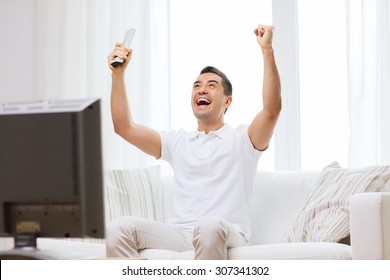 Sports, Happiness And People Concept - Smiling Man Watching Sports On Tv And Supporting Team At Home