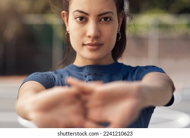 Sports helps to develop mental and physical toughness. Portrait of a sporty young woman stretching her arms on a sports court.