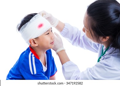 Sports Injury. Athlete Little Asian (thai) Boy In Blue Sportswear With Trauma Of The Head Crying, Bloody On Bandage. Doctor Makes Bandage On Head Patient, On White Background. Studio Shoot. Side View.