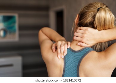 Sports injury concept. Athletic woman feeling pain in her neck against blurred background. Pain after home workout - Shutterstock ID 1821410372