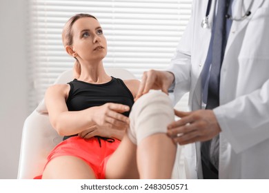 Sports injury. Doctor examining patient's knee in hospital, closeup - Powered by Shutterstock