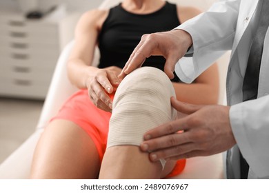 Sports injury. Doctor examining patient's knee in hospital, closeup - Powered by Shutterstock