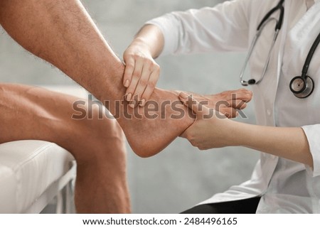 Sports injury. Doctor examining patient's foot in hospital, closeup