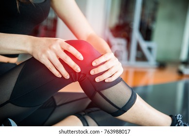 Sports Injury At Knee In Fitness Training Gym. Training And Medical Concept. Health Care And Sport Exercise Concept. Pain Of Body Part And Bone Broken Theme. First Aid And Safety First Theme