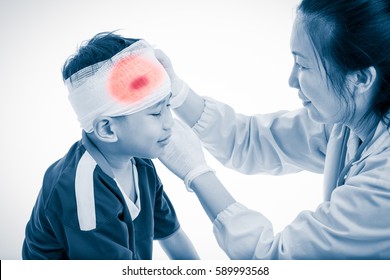 Sports Injury. Sad Asian Boy With Trauma Of Head Crying, Bloody On Bandage. Doctor Makes Bandage On Head Patient, On White Background. Color Increase Blue Skin And Red Spot Indicating Location Of Pain