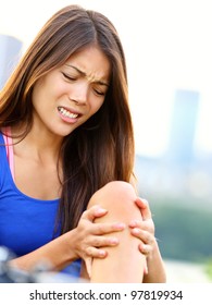 Sports Injury. Woman With Pain In Knee Joint Sport Workout. Young Woman Fitness Model Outside.