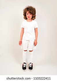 Sports Injury. Youth European Soccer Player In White Uniform Isolated On White Background. Studio Shot. Full Body. Boy Standing And Crying.