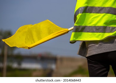 Sports judge in lemon vest and yellow flag on the motocross track
