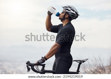 Sports man with a bike drinking water bottle doing fitness training or workout on sky mockup background. Healthy, professional athlete cyclist with a bicycle during cycling cardio exercise in nature
