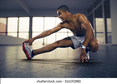 Sports. Man at the gym doing stretching exercises and smiling on the floor - Powered by Shutterstock