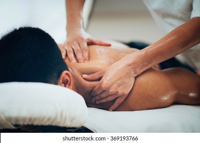 Sports massage. Massage therapist massaging shoulders of a male athlete, working with Trapezius muscle. Toned image