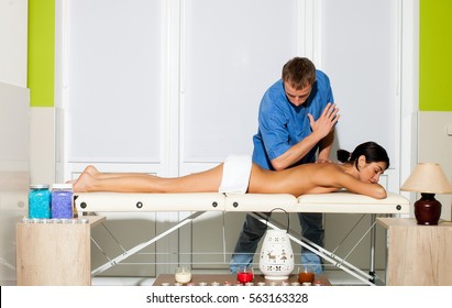 Sports Massage. Massage Therapist Massaging Shoulders Of A Male Athlete, Working With Trapezius Muscle. Toned Image. Beautiful Young Girl Having Massage In Spa Salon. The Love Story.