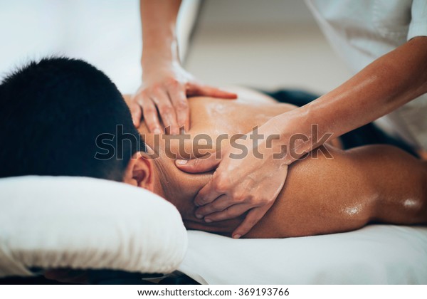Sports\
massage. Massage therapist massaging shoulders of a male athlete,\
working with Trapezius muscle. Toned\
image