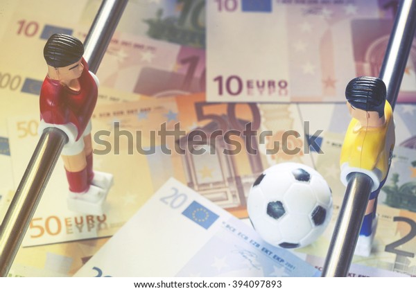 Sports and money. Concept\
about money spending in football (soccer), sports betting and\
manipulated fixed matches. Selective focus image cross processed\
for retro look