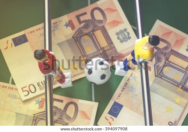Sports and money. Concept\
about money spending in football (soccer), sports betting and\
manipulated fixed matches. Selective focus image cross processed\
for retro look