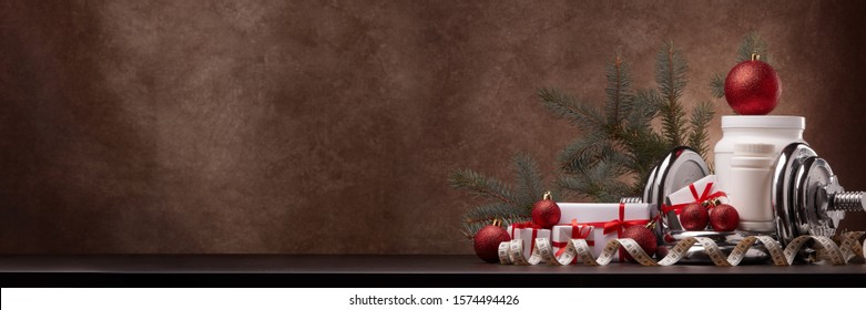 Sports Nutrition (supplements), Sports Equipment, Fir Branch,  Gift Boxes, Christmas Ornaments On Dark Brown Background With Copy Space. Fitness, Sport, Healthy Lifestyle Concept. New Year. Christmas.