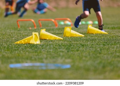 Sports Outdoor Training Trail At Grass Field. Sports Practice Summer Camp For Children. Line Of Yellow Cones And Orange Hurdles. A Young Boy Attending Sports Education Class At Summer Camp