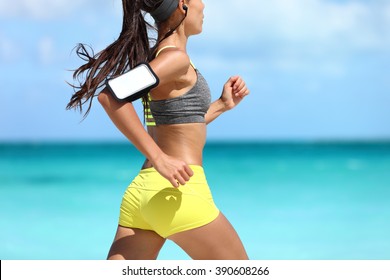 Sports phone armband fitness jogger exercising on beach - cardio workout. Midsection closeup of female athlete runner jogging wearing smartphone sleeve and earphones. Glutes training. - Powered by Shutterstock