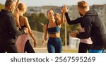 Sports and running races. Happy young woman runner giving high five to other people after successful result in race. Smiling Caucasian woman in sports outfit runs and greets spectators at finish line.