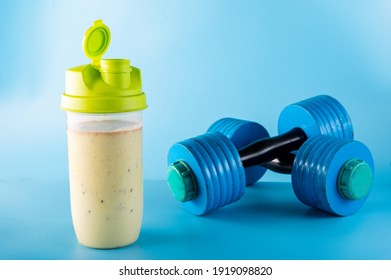 Sports shaker with sports nutrition. Protein shaker. Dumbbells. Blue dumbbells on a blue background. - Shutterstock ID 1919098820