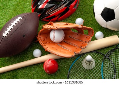 Sports Shop, Youth Athletics And Team Sport Competition Conceptual Idea With Various Types Balls (soccer, Baseball, Football, Golf Ball), Wooden Bat And Bike Helmet Isolated On Green Grass Background