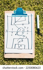 Sports, soccer field and clipboard planning a strategy for a group mission, target or tactics for goals. Solutions, teamwork and coach drawing winning tactics or ideas on grass in a football stadium