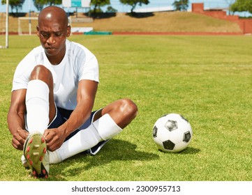 Sports, soccer and man tie his shoes on an outdoor field before game, workout or training. Fitness, football and African male athlete tying laces to prepare for match, exercise or practice on pitch. - Powered by Shutterstock