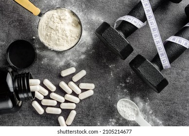 Sports supplements and dumbbells close-up on a dark background. Flat lay composition with protein and creatine. - Shutterstock ID 2105214677