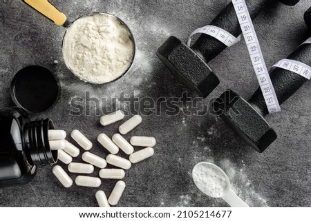Sports supplements and dumbbells close-up on a dark background. Flat lay composition with protein and creatine. 商業照片 © 
