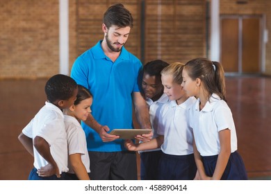 Sports teacher and school kids using digital tablet in basketball court at school gym - Powered by Shutterstock
