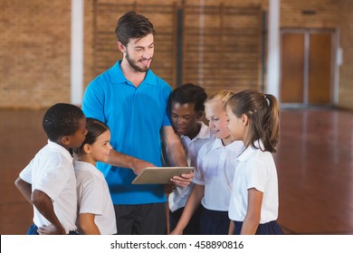 Sports teacher and school kids using digital tablet in basketball court at school gym - Powered by Shutterstock