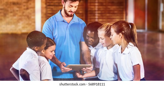 Sports teacher and school kids using digital tablet in basketball court at school gym - Powered by Shutterstock