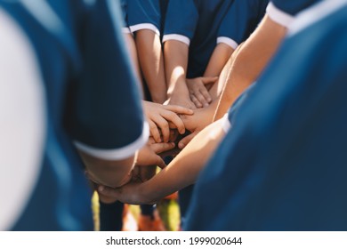 Sports team stacking hands together in a group. Happy children teammates motivated in a team. Team building activities and boosting sports players' morale. Schoolboys building team spirit before game