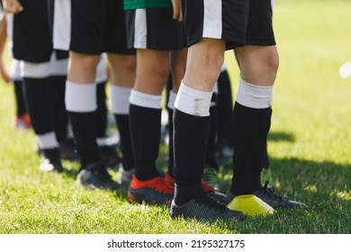 Sports Team Standing On Grass Venue. Closeup Picture Of Soccer Player's Feet. Footballers Standing In A Row On Training