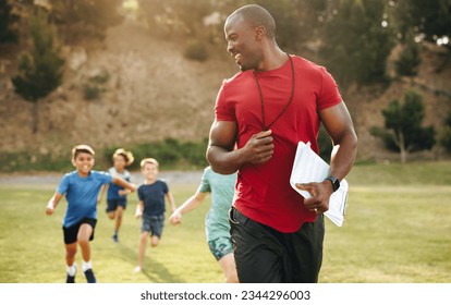 Sports trainer coaching elementary school children. Male PE teacher having a running session with group of kids in a school ground. Sports education in primary school.