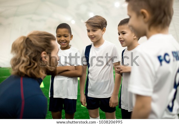 Sports trainer consulting his football\
team of four boys before new game or\
competition