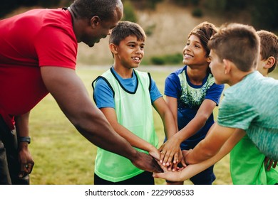 Sports trainer having a huddle with his team in a school field. Rugby coach giving his students a motivational talk before practice. Sports mentorship in elementary school. - Powered by Shutterstock